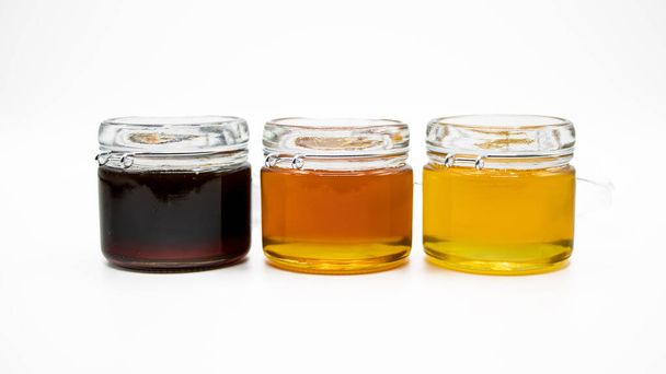 Баночки з трьома різними видами меду ізольовані на білому тлі
 - Фото, зображення