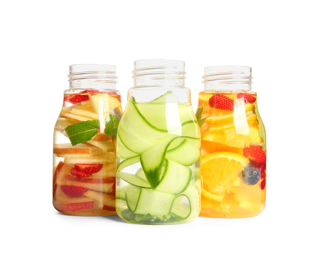 Пляшки наповненої води з різними нарізаними фруктами на білому тлі
 - Фото, зображення