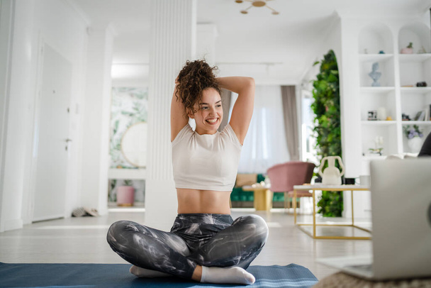 One young woman caucasian female yoga stretching practice at home online via laptop computer internet instructions course - Fotó, kép