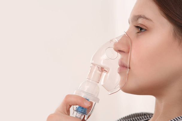 Cute girl using nebulizer for inhalation on white background, closeup. Space for text - Zdjęcie, obraz