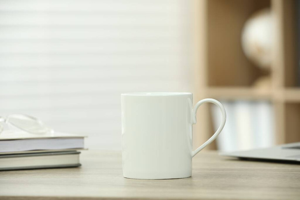 White ceramic mug and notebooks on wooden table indoors - Фото, изображение
