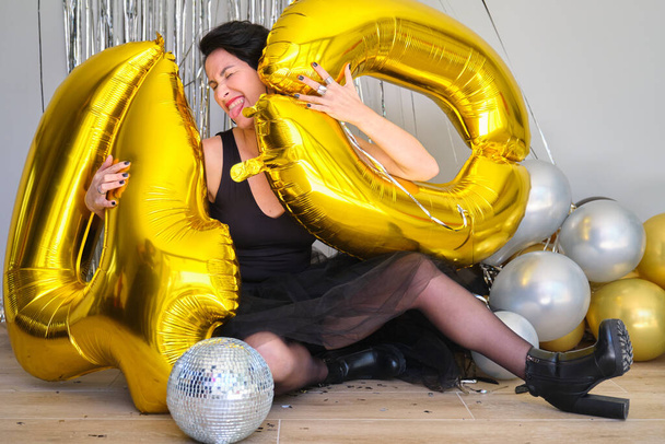 Λευκή γυναίκα σε πάρτι 40 γενεθλίων με 40 χρυσά μπαλόνια στο πάτωμα.. - Φωτογραφία, εικόνα