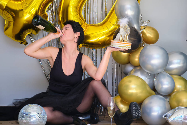 Caucasian woman drinking champagne from bottle celebrating her 40 birthday in a party. - Fotografie, Obrázek