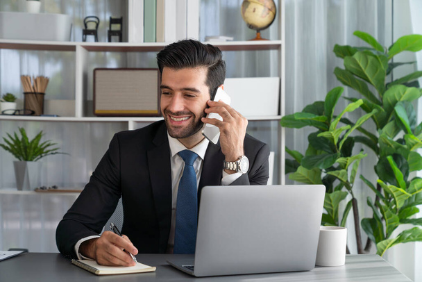 Ahkera liikemies kiireinen puhua puhelun asiakkaiden kanssa työskennellessään kannettavan tietokoneen toimistossaan käsitteenä modernin ahkera toimistotyöntekijä elämäntapa matkapuhelimella. Kiihkeä - Valokuva, kuva