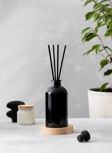 Bamboo sticks in a black bottle with indoor perfumes. Glass diffuser with fragrance for home. Aromatherapy. - Fotografie, Obrázek