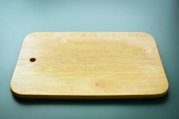 brązowa drewniana deska do cięcia na zielonym tle, sprzęt do gotowania w kuchni - Zdjęcie, obraz