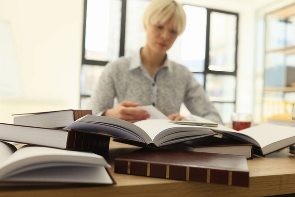 短い髪の女性は、図書館のテーブルに座って大学院の仕事のための厚い本の中で情報を検索します。女性学生はキャリア成長のための知識を得る - 写真・画像