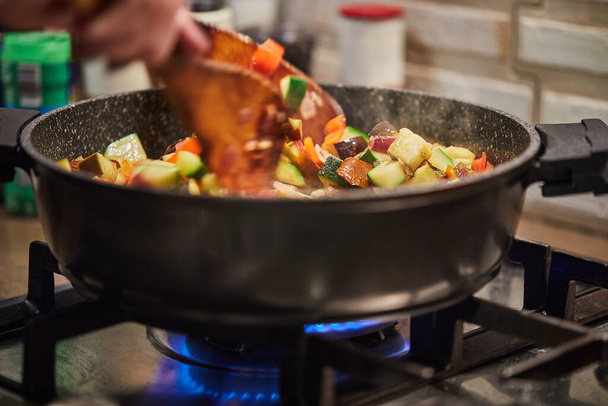 French cuisine ratatouille salad shchef stirs in frying pan on gas stove. - Foto, Bild