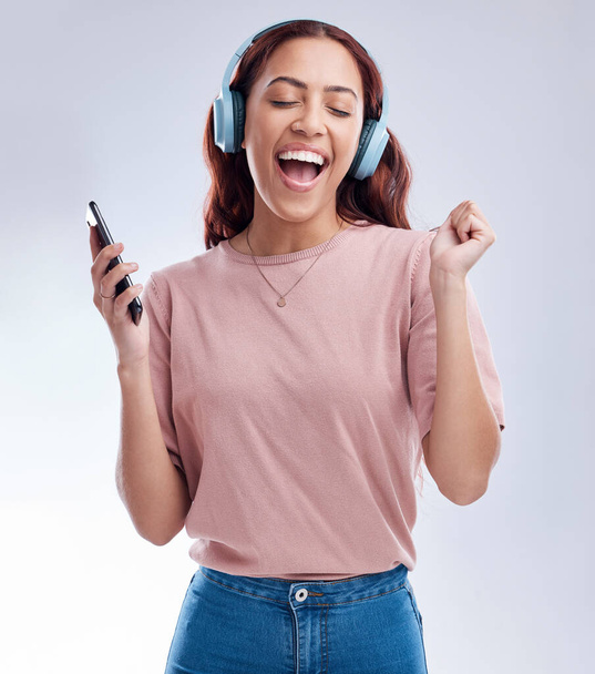 Мобільний, навушники або щаслива жінка танцює на музиці або співає радіо пісні в студії на білому тлі. Танцювати, посміхатися або захоплююча дівчина трансляція або прослуховування аудіо-плейлиста з мобільним телефоном або енергією
. - Фото, зображення
