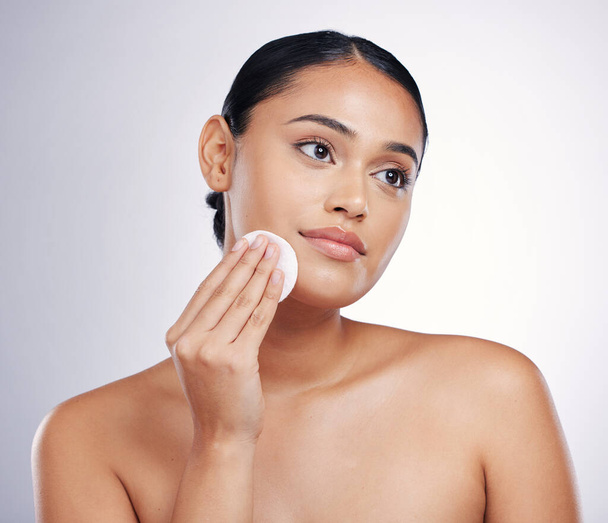 Face, cleaning and cotton on skin of a woman in studio for natural beauty, dermatology or cosmetics. Female person with skincare wipe in hand for glow, healthy and clean facial on a white background. - Photo, image