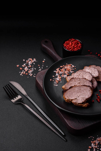 Смачний яловичий стейк з сіллю, спеціями та травами на керамічній тарілці на темному бетонному фоні
 - Фото, зображення