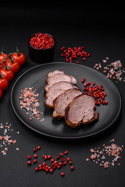 Смачний яловичий стейк з сіллю, спеціями та травами на керамічній тарілці на темному бетонному фоні
 - Фото, зображення