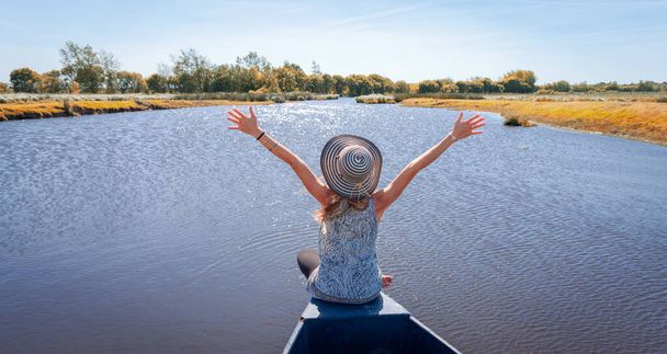 Briere Marshland- Happy woman tourist in wooden boat in marsh- France- natural regional park of Briere- Pays de la Loire - Photo, Image