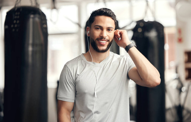 Fitness, portrait of man with earphones and in gym happy for health wellness. Exercise or training, sportswear and smiling male athlete listening to music or podcast for motivation for workout - 写真・画像