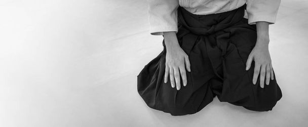 Woman practicing aikido martial art in a dojo background. Seiza position. - Foto, afbeelding