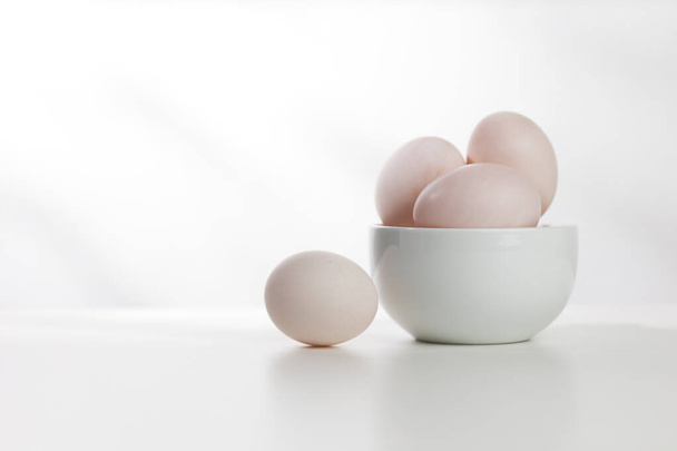 Beyaz ahşap bir masada beyaz bir kasede ördek yumurtaları. - Fotoğraf, Görsel