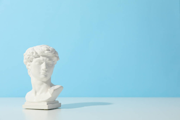 Ancient head on white table against blue background - Photo, Image
