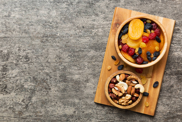 健康的なスナック:テーブルの背景にボウルにナッツとドライフルーツを混合,アーモンド,パイナップル,クランベリー,チェリー,アプリコット,カシュー. - 写真・画像