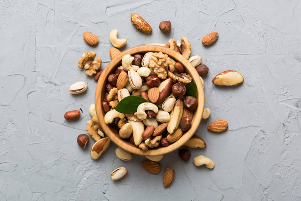 mixed nuts in bowl. Mix of various nuts on colored background. pistachios, cashews, walnuts, hazelnuts, peanuts and brazil nuts. - Foto, Imagen