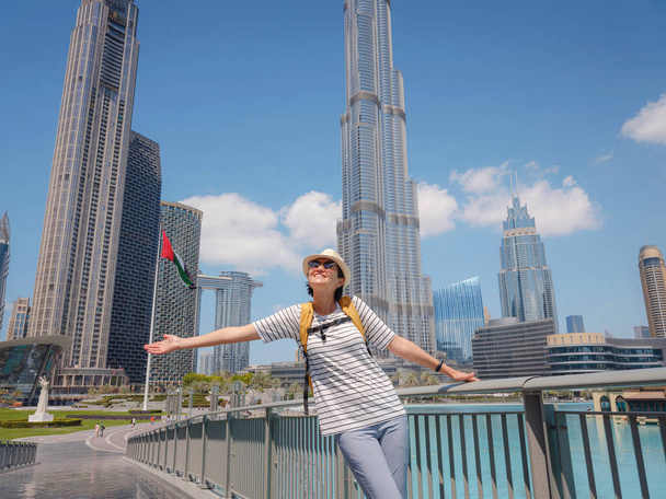 Desfrutando de viagens em Emirados Árabes Unidos. Jovem com mochila amarela caminhando no Dubai Downtown no dia ensolarado de verão. - Foto, Imagem