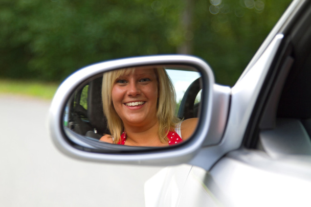 Женщина смотрит в зеркало автомобиля
 - Фото, изображение