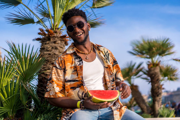 Portrait of a black ethnic man enjoy summer vacation on the beach with a watermelon having fun - Foto, afbeelding
