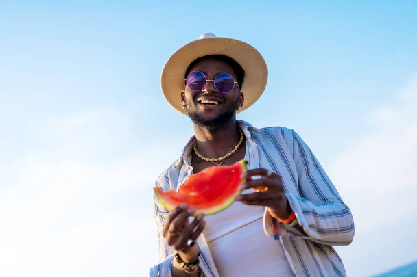 Black ethnic man enjoy summer vacation at the beach eating a watermelon - Valokuva, kuva