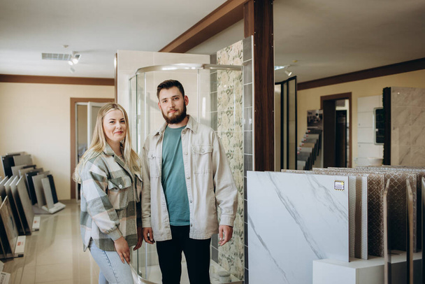 Beautiful young couple choosing ceramic tiles for their house repairment in the building shop - Valokuva, kuva