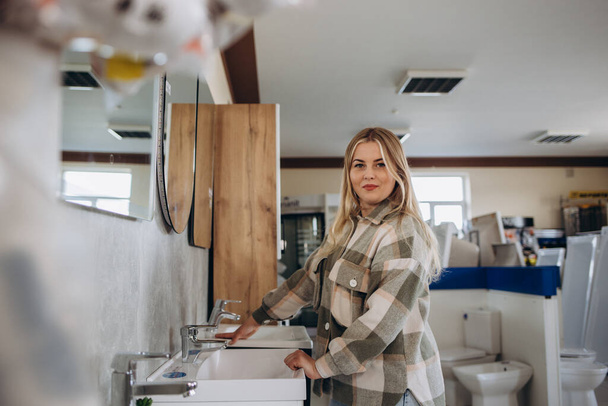 Positiivinen nainen asiakas valitsee pesuallas kylpyhuoneessa asennus myymälä. - Valokuva, kuva
