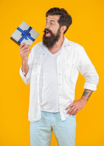 amazed birthday man with purchase in studio. birthday man with purchase on background. photo of birthday man with purchase box. caucasian birthday man with purchase isolated on yellow. - Foto, Imagen