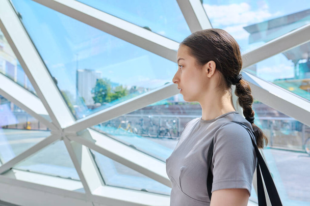 Portrait of a teenage girl inside a modern building, urban city background, copy space. Young female high school student profile view, lifestyle concept - Foto, Imagen