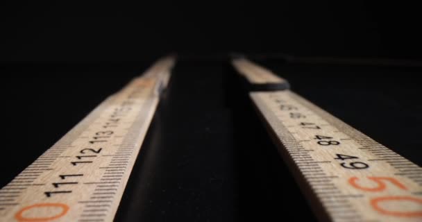 Zbliżenie drewnianej linijki na czarnym tle. Składana drewniana linijka - Materiał filmowy, wideo