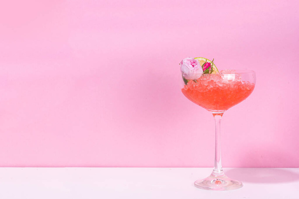 Frozen rose daiquiri or margarita cocktail, champagne, pink rose wine alcohol drink with roses flowers and lime slices - 写真・画像