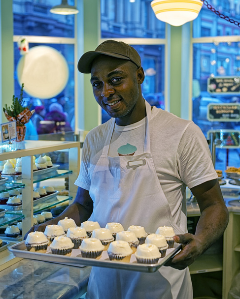 Homme noir avec des cupcakes sur le plateau
 - Photo, image