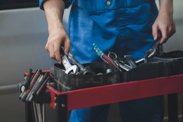 Professional car mechanics searching for auto repair tools in tool racks, all kinds of auto specialists, expert auto repair and accredited auto repair centers. - 写真・画像