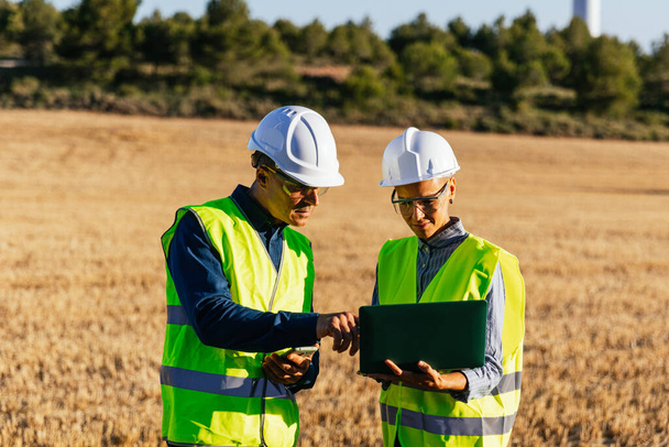 Engineers using a laptop while working together in the field. Engineering, technology and industry concept. - Photo, Image