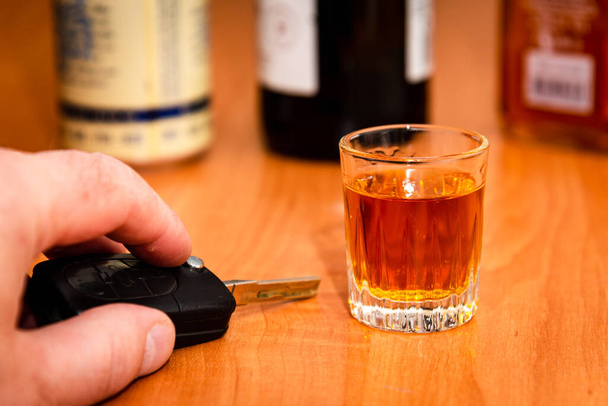Do not drink and drive. Drunk man hand with glass alcohol,car key in hand taking car keys. - Fotoğraf, Görsel