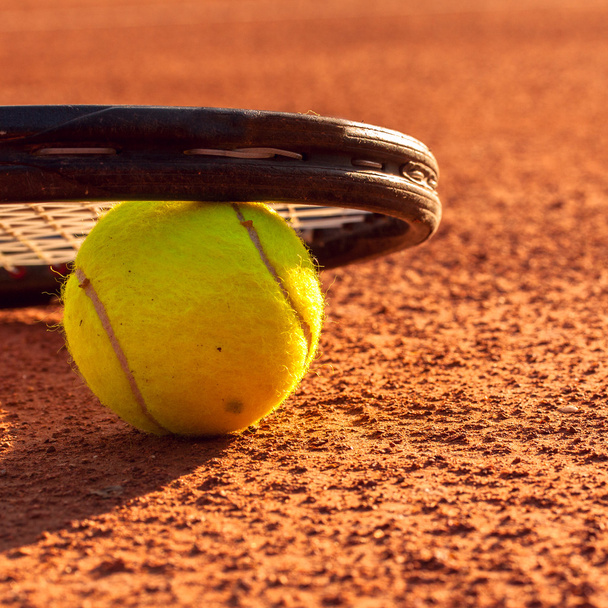 Tennis ball and racquet on a tennis clay court - Fotoğraf, Görsel