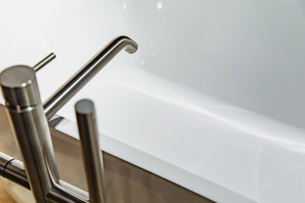 Grifo de metal moderno sobre bañera blanca - Foto, Imagen