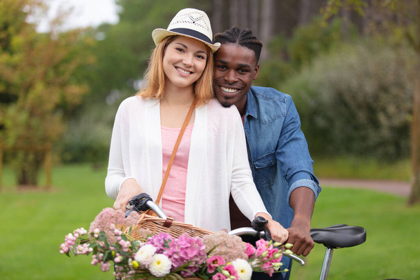 happy mixed couple posing on a bike - 写真・画像