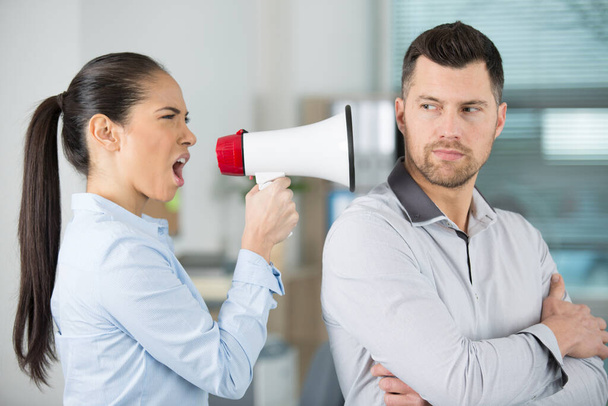 angry female boss shouting through megaphone at oblivious male employee - Valokuva, kuva