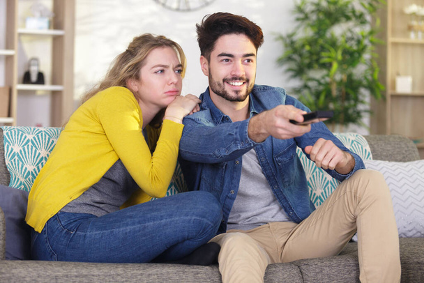 couple sitting on the sofa using a control remote - Фото, изображение