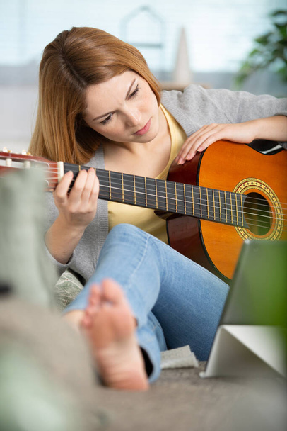 young woman playing a guitar at home - 写真・画像