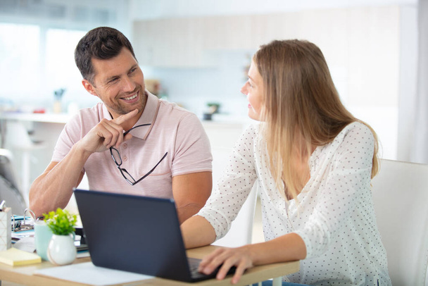 smiling couple looking at laptop in kitchen - Φωτογραφία, εικόνα