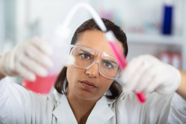 frowning female chemist using a pipette - Valokuva, kuva