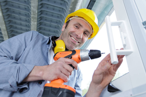 portrait of happy man in uniform working with electrical screwdriver - Zdjęcie, obraz