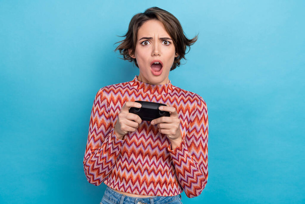 Photo of shocked impressed lady wear striped top loosing playstation game open mouth isolated blue color background. - Zdjęcie, obraz