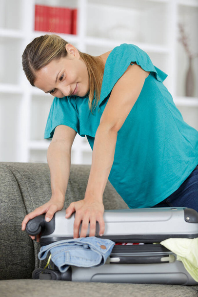 woman trying to compress things in the suitcase - Photo, image