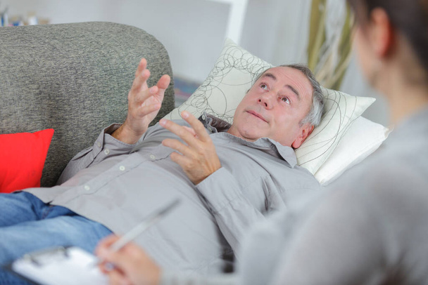 miserable depressed man on the sofa talking to professional - Photo, Image