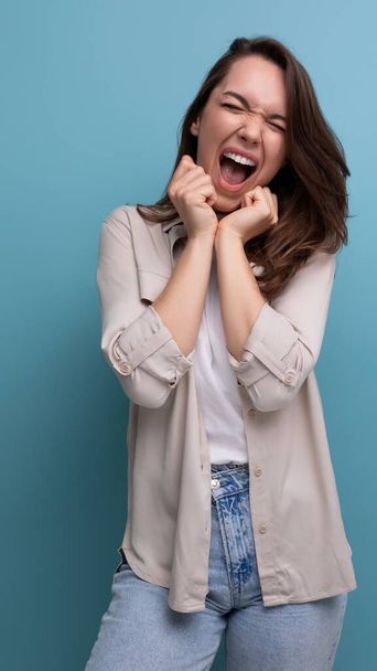 χαμογελαστή όμορφη μελαχρινή 30χρονη γυναίκα με πουκάμισο και τζιν είναι ευτυχισμένη. - Φωτογραφία, εικόνα